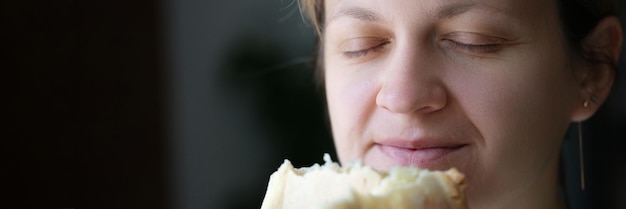 Mulher feliz com os olhos fechados, segurando o pão branco, cozinhando o delicioso pão fresco em casa conceito