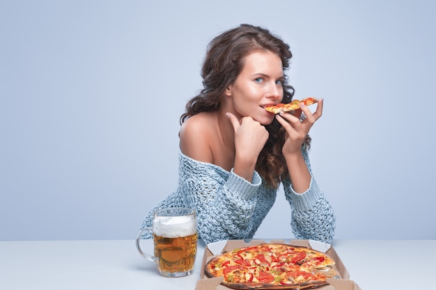 Mulher feliz com pizza e cerveja no espaço cinza, espaço para texto