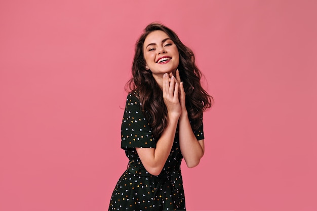 Mulher feliz com roupa de bolinhas rindo na parede rosa