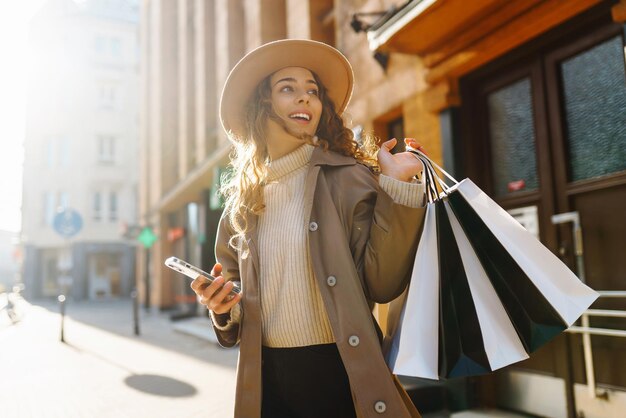 Mulher feliz com sacos de compras caminhando na rua Compras discotecas de sexta-feira negra conceito de venda