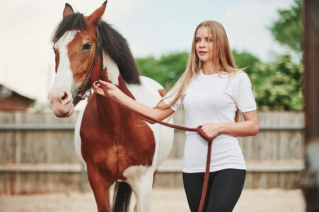 Mulher feliz com seu cavalo no rancho durante o dia.