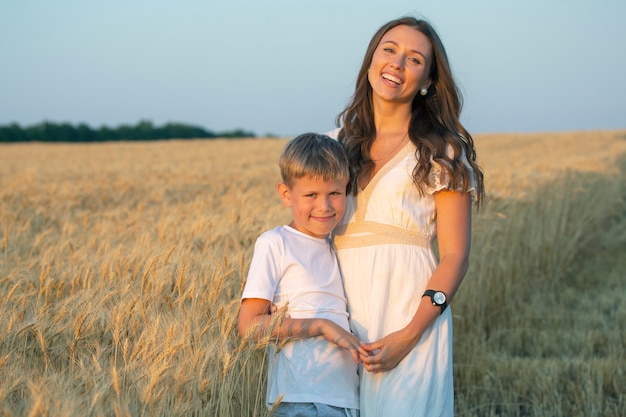Mulher feliz com seu filho lindo em um campo de trigo. amor e maternidade