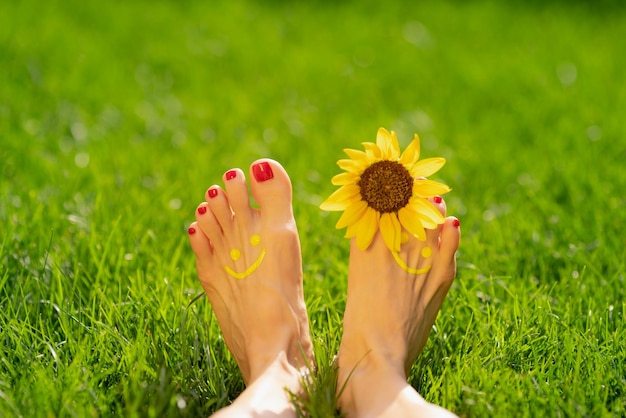 Mulher feliz com sorriso nos pés ao ar livre Pessoa deitada na grama verde primavera Ecologia e conceito de estilo de vida saudável