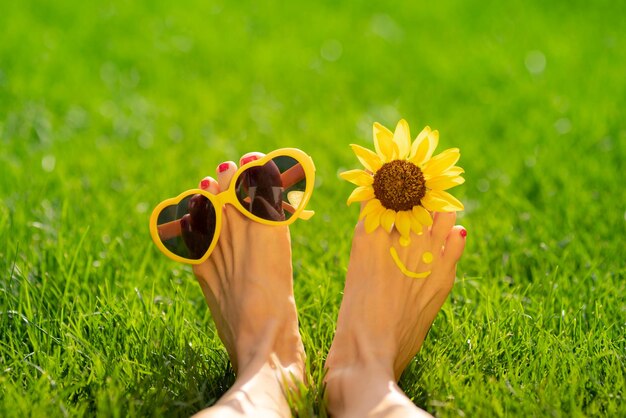 Mulher feliz com sorriso nos pés ao ar livre Pessoa deitada na grama verde primavera Ecologia e conceito de estilo de vida saudável