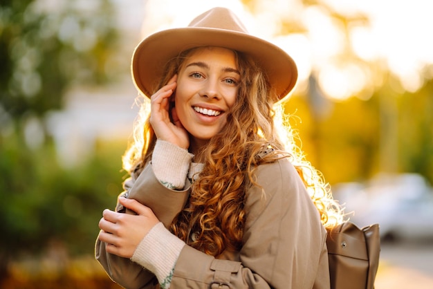 Mulher feliz com suéter estiloso e chapéu ao ar livre no parque de outono em xadrez Mulher gosta da natureza do outono
