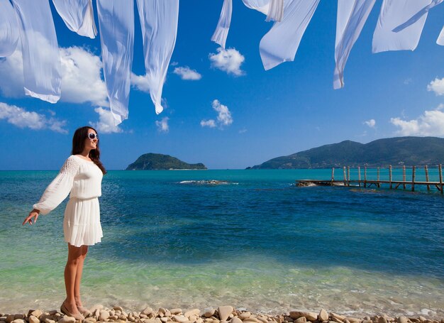 Mulher feliz com vestido branco de verão na praia