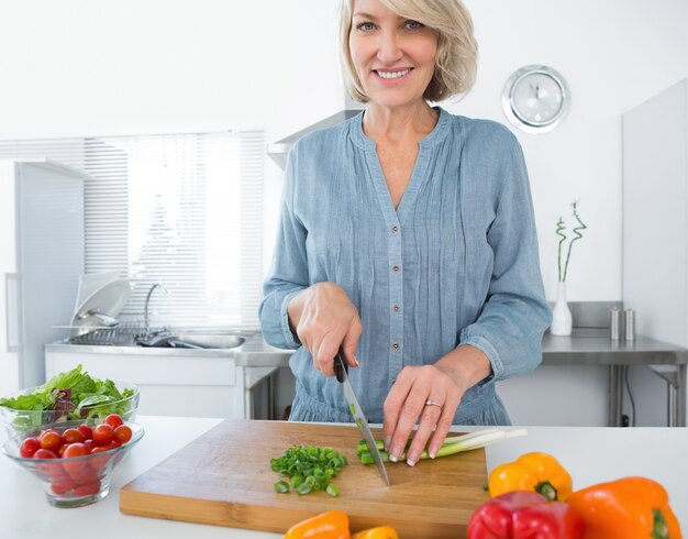 Mulher feliz cortando vegetais