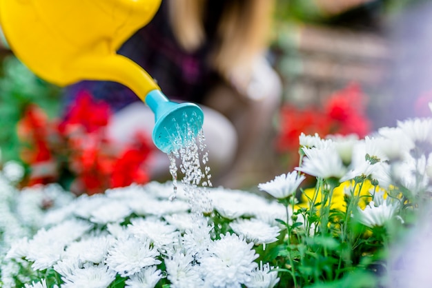 Mulher feliz cuidando de suas plantas (e regando elas) em seu jardim.