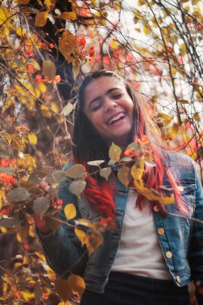 Mulher feliz de pé contra a árvore