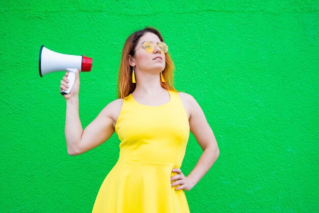 Foto mulher feliz de pé contra a parede amarela