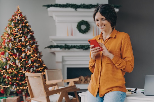 Mulher feliz digitando no celular durante as férias de Natal em casa