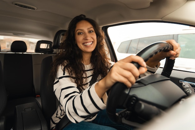 Foto mulher feliz dirigindo carro sorrindo para a câmera posando em auto