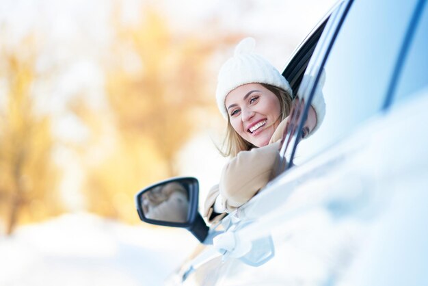 Mulher feliz dirigindo o carro no inverno nevado. Foto de alta qualidade