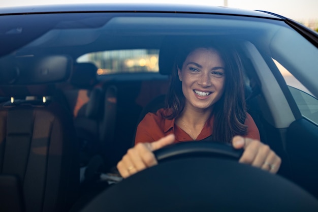 Foto mulher feliz dirigindo um carro e sorrindo bonito jovem sucesso mulher morena feliz está dirigindo um carro retrato de uma motorista feliz dirigindo o carro com cinto de segurança