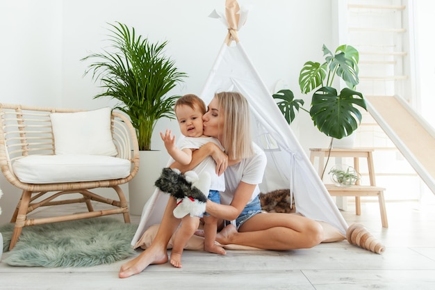 Mulher feliz e a filha a brincar de wigwam em casa.