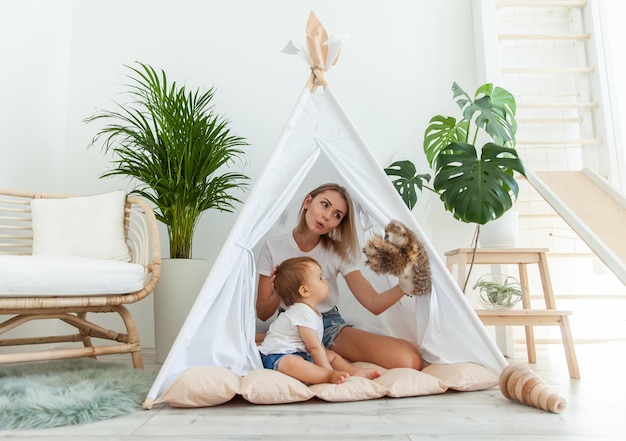 Mulher feliz e a filha a brincar de wigwam em casa.