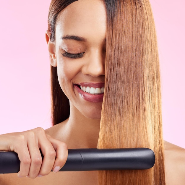 Foto mulher feliz e alisador de cabelo para tratamento de salão de beleza e garota no fundo do estúdio mulher feminina e ferramenta para textura e volume de cosméticos com brilho e brilho com sorriso e spa