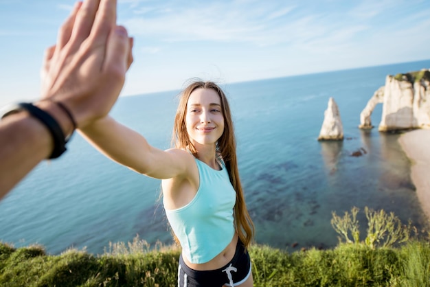 Mulher feliz e brincalhona em roupas esportivas dando cinco outdors no fundo da costa rochosa