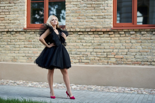 Foto mulher feliz e elegante ao ar livre usando um vestido preto e sorrindo para a câmera