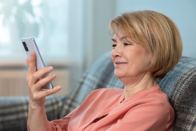 Mulher feliz e positiva, idosa senhora madura está olhando para a tela de seu telefone celular e