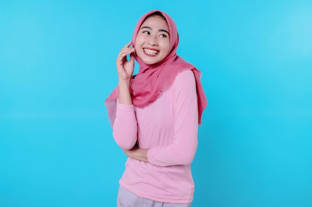 Mulher feliz e sorridente com aparência atraente e vestindo uma camiseta rosa e hijab mostrando um sorriso de bom humor