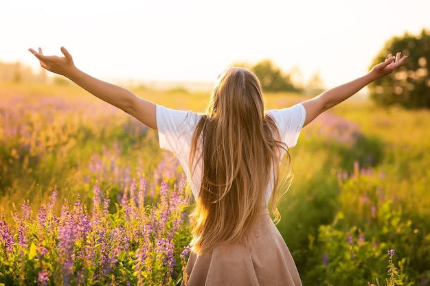 Mulher feliz e sorridente em um campo roxo ao pôr do sol no conceito de liberdade