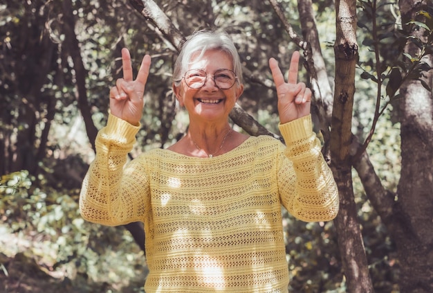 Foto mulher feliz e sorridente na floresta a desfrutar da natureza e da liberdade a olhar para a câmara a fazer gestos