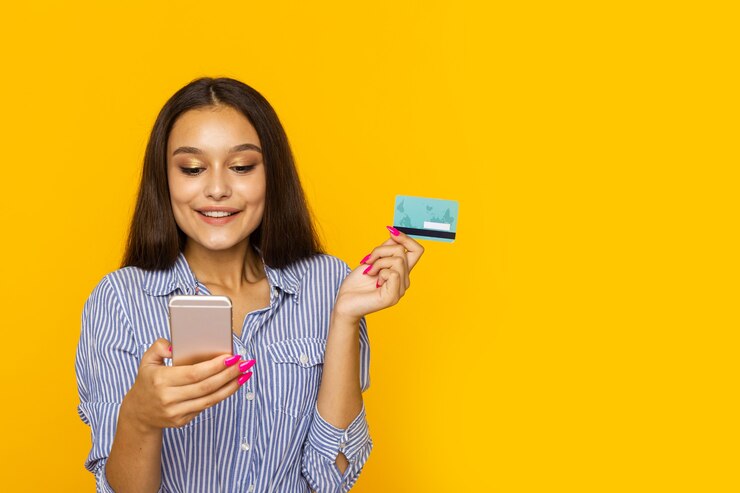 Mulher feliz e surpresa com telefone e cartão de crédito. Conceito de compras online.