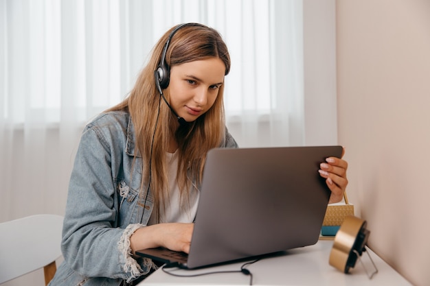 Foto mulher feliz em casa olhando para um laptop com fones de ouvido fazendo videochamada