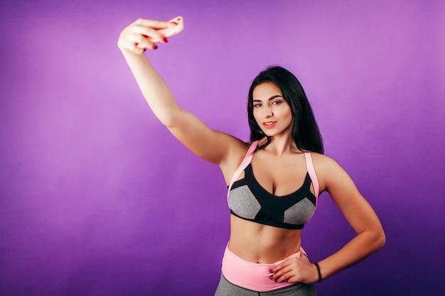 Mulher feliz em forma fazendo selfie em smartphone no estúdio