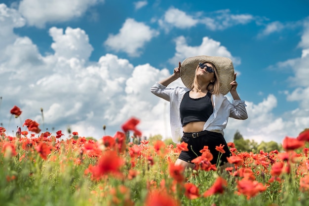 Mulher feliz em um pano casual no campo de papoulas Aproveite o horário de verão grátis. natureza