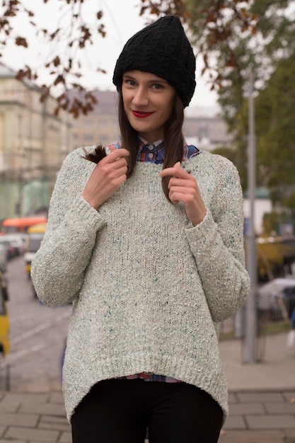 Mulher feliz em um suéter quente e boné na cidade