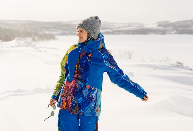 Mulher feliz em um terno de inverno no contexto de um campo coberto de neve