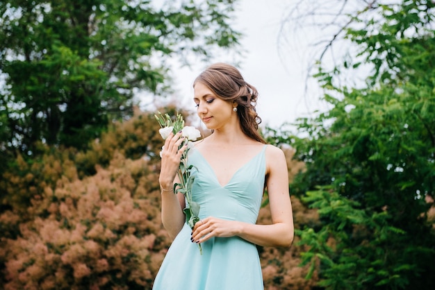 Mulher feliz em um vestido longo turquesa em um parque verde