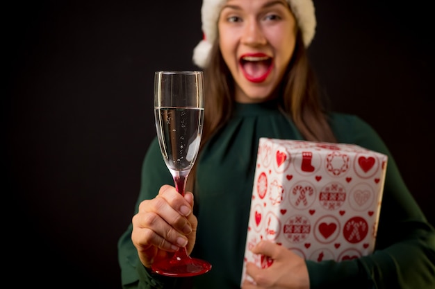 Mulher feliz em um vestido verde com champanhe e presente de Natal