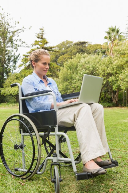 Mulher feliz em uma cadeira de rodas usando um laptop