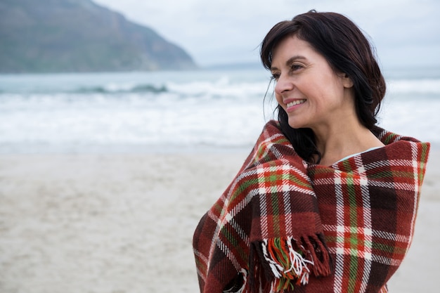 Mulher feliz, envolvida em xale na praia