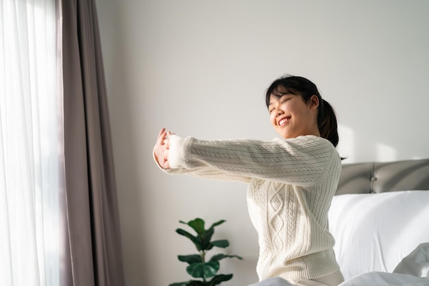Foto mulher feliz estendendo os braços na cama pela manhã