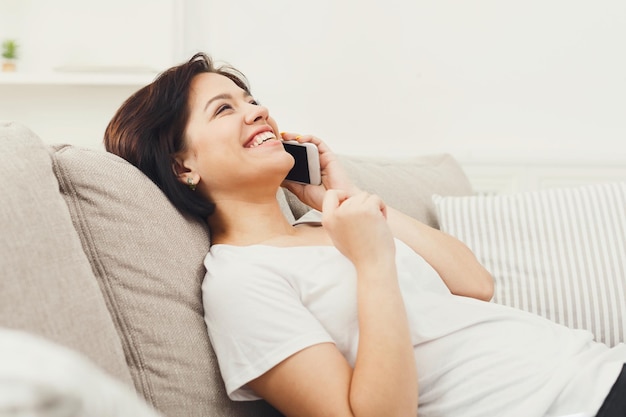 Mulher feliz falando no smartphone em um sofá confortável em casa, copie o espaço