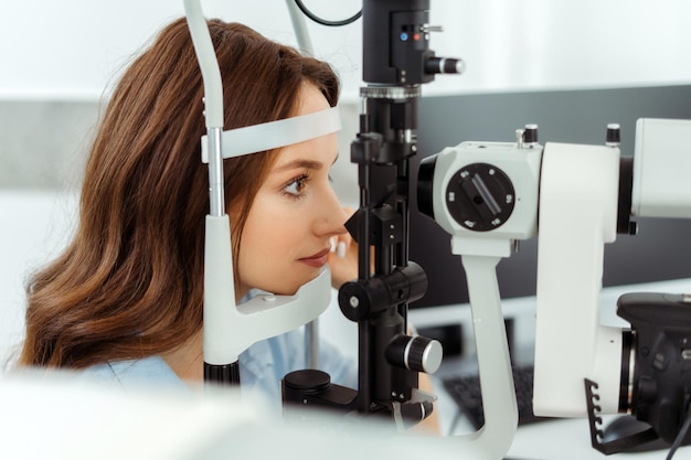 Mulher feliz fazendo medição da visão com lâmpada de fenda óptica exame médico