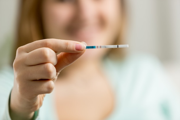 Mulher feliz fazendo teste de gravidez com duas linhas