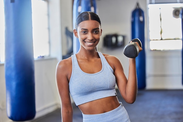 Mulher feliz fitness e exercício com halteres na academia para objetivos de bem-estar corporal forte e estilo de vida saudável Retrato de esportes femininos indianos e felicidade com pesos para treinamento de exercícios e poder