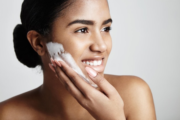 Mulher feliz lava o rosto com espuma de sabão