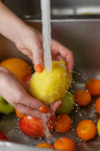 Foto mulher feliz lavando frutas na cozinha bananas tangerinas maçãs