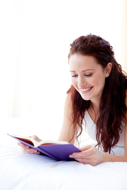 Foto mulher feliz lendo um livro na cama