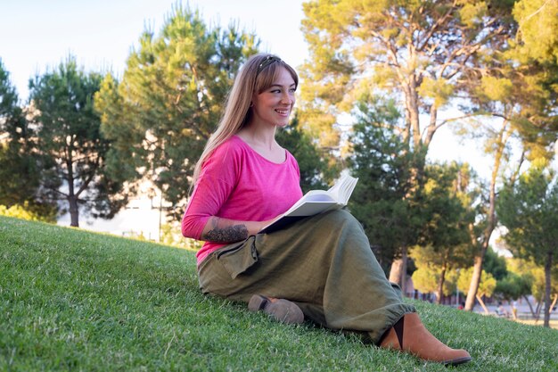 Foto mulher feliz lendo um livro no parque