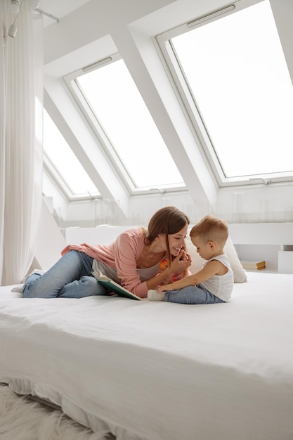 Mulher feliz lendo um livro para o filho na cama