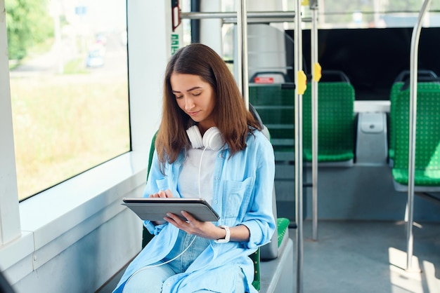 Mulher feliz lendo um tablet ou ebook em uma estação de trem enquanto espera por transporte público