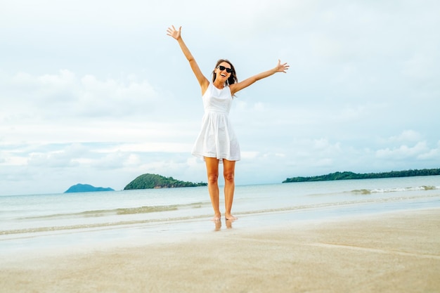 Mulher feliz liberdade com os braços erguidos na praia em dia ensolarado. Conceito de felicidade e liberdade