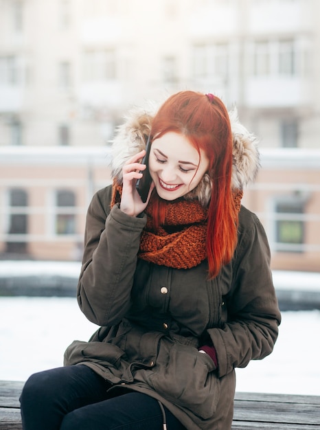 Mulher feliz ligando para o celular na rua no inverno